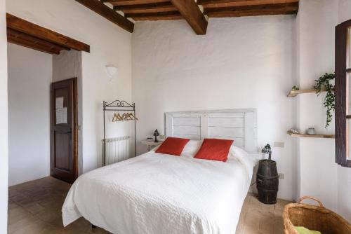 a bedroom with a white bed with two red pillows at Agriturismo Quarantallina in Buonconvento