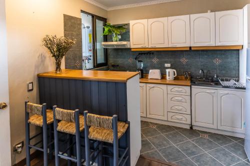 a kitchen with white cabinets and a counter with stools at Montaña Blanca in Farellones