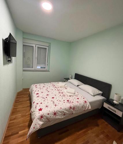 a bedroom with a bed with red flowers on it at Stan na dan Milena in Trebinje