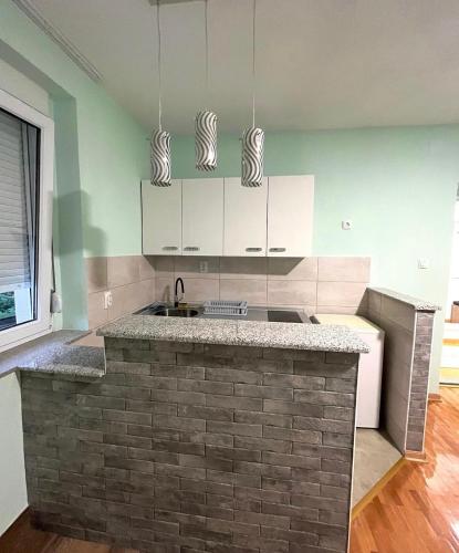 a kitchen with white cabinets and a brick counter top at Stan na dan Milena in Trebinje