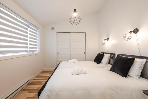 two beds in a white bedroom with a window at Le Memph Chouette spacious comfortable condo cottage eco responsible 3 bedrooms private garage - hot tub & pool Memphrémagog Lake in Magog-Orford