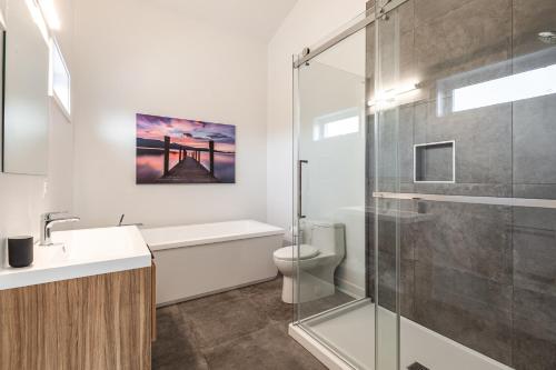 a bathroom with a shower and a toilet and a sink at Le Memph Chouette spacious comfortable condo cottage eco responsible 3 bedrooms private garage - hot tub & pool Memphrémagog Lake in Magog-Orford