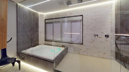 a large bathroom with a tub and a window at Motel DUBAI BH in Belo Horizonte