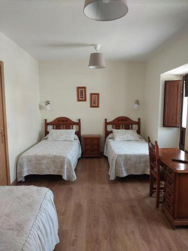 a bedroom with two beds and a table and a desk at Hotel Rural Cabrales in Carreña de Cabrales 