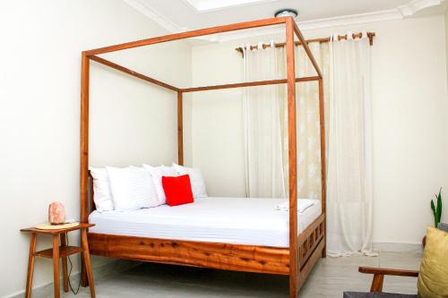 1 dormitorio con cama de madera con dosel y almohada roja en Kwale Residence, en Kiembi Samaki