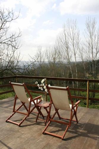two chairs and a table on a wooden deck at Verde Água Agroturismo e Agricultura Biológica in Couto