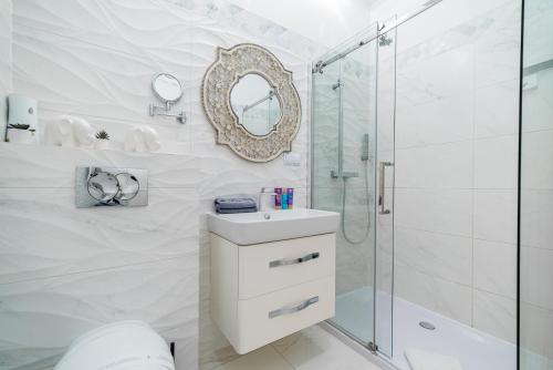 La salle de bains blanche est pourvue d'un lavabo et d'une douche. dans l'établissement Apartament Glamour Vip, à Ustka