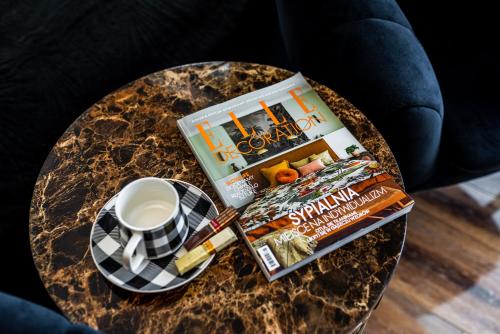 a table with a book a cup of coffee and a magazine at Apartament Glamour Vip in Ustka
