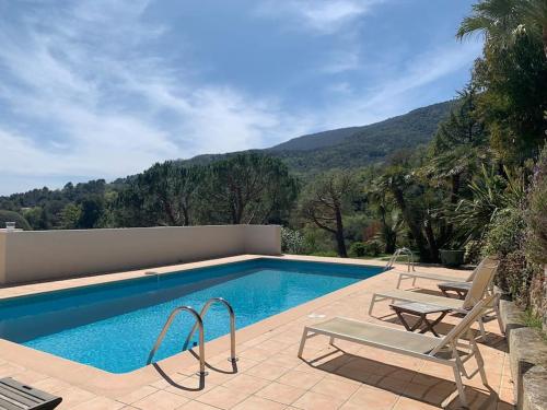 une piscine avec deux chaises longues à côté dans l'établissement South of France Villa, à Carros