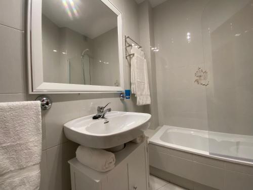 a white bathroom with a sink and a bath tub at LALIN CENTRO URBANO, CÓMODO Y FUNCIONAL in Lalín