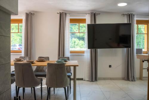 a dining room with a table and a television at Chalet HerMes arT in Idrija