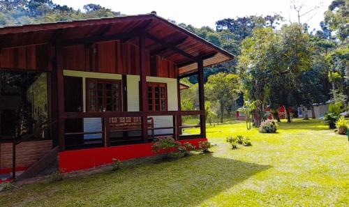 a small house in a field of grass with trees at Pousada Bosque do Visconde in Visconde De Maua