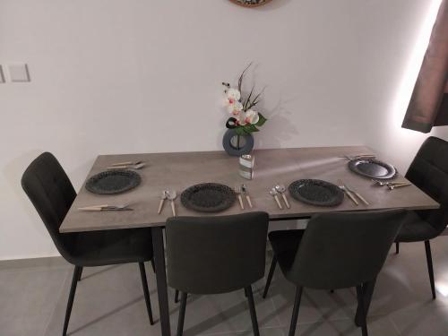 a table with chairs and plates and a vase with flowers at St Gaetan Accomodation 6B in Hamrun