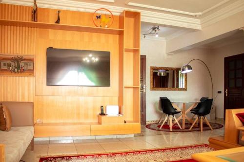 ein Wohnzimmer mit einem TV und einem Tisch in der Unterkunft The Downtown Jewel - Centre Marrakech in Marrakesch