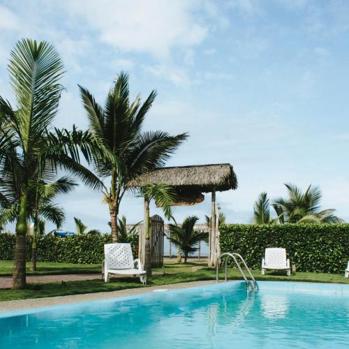 a swimming pool with two chairs and a gazebo at Ayampe Guest House in Ayampe