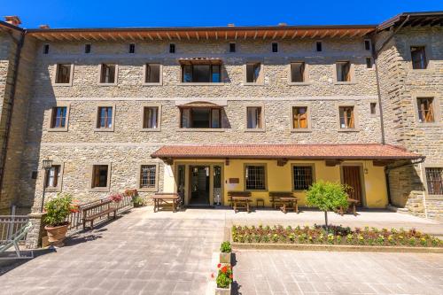 a large stone building with a courtyard in front of it at Casa PerFerie “PASTOR ANGELICUS” in La Verna