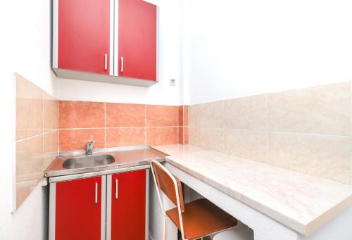 a kitchen with red cabinets and a sink at Apartmani i sobe Radojičić in Bijela