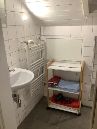 a small bathroom with a sink and a shelf with towels at Villa Walter in Leinfelden-Echterdingen