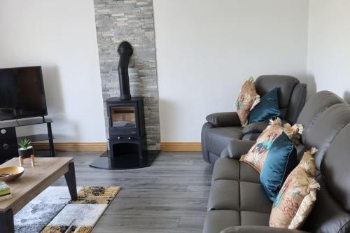 a living room with a couch and a wood stove at Grace's Place with Hot Tub & Games Room in Carrickfergus