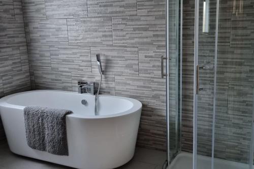a bathroom with a tub and a glass shower at Grace's Place with Hot Tub & Games Room in Carrickfergus