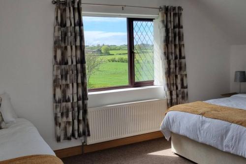 a bedroom with a window with a view of a green field at Grace's Place with Hot Tub & Games Room in Carrickfergus
