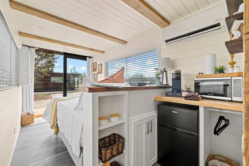 eine Küche in einem winzigen Haus mit Spüle und Mikrowelle in der Unterkunft New The Sunrise Cozy Container Home in Fredericksburg
