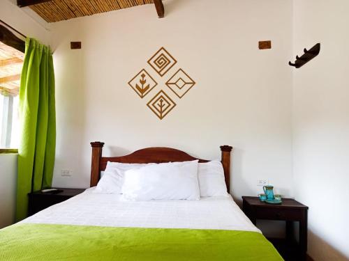 a bedroom with a bed with a green blanket at Posada El Artesano De Raquira in Ráquira