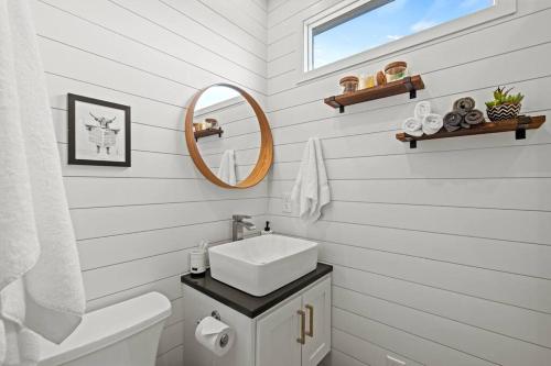 a white bathroom with a sink and a mirror at New! The Texas Longhorn-Luxury Container Home in Fredericksburg