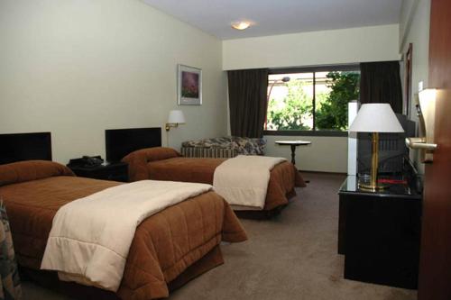 a hotel room with two beds and a couch at Hotel Austral Bahía Blanca in Bahía Blanca