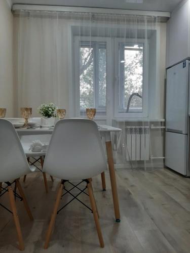 eine Küche mit einem Tisch, 2 Stühlen und einem Kühlschrank in der Unterkunft Всё-всё новое "от и до" in Oral