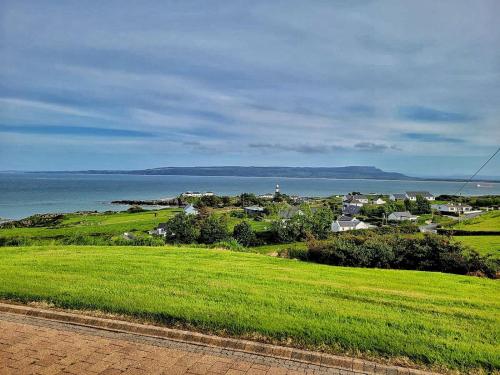 a green field with a town and the ocean at Lighthouse Farm in Greencastle