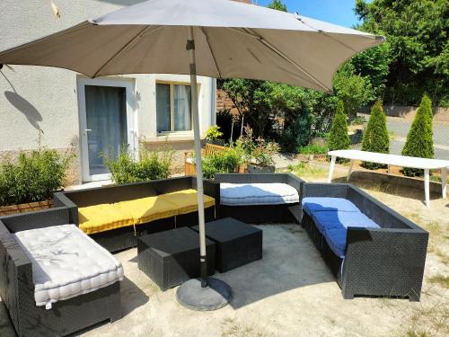 a patio with an umbrella and couches and a table at L'échappée Comtoise in Baume-les-Dames