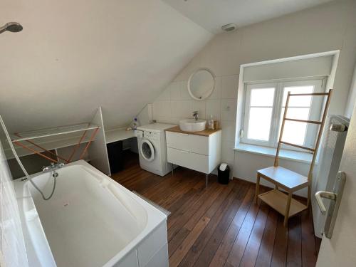 a bathroom with a tub and a sink and a washing machine at Charmant F3 à Gérardmer Centre in Gérardmer
