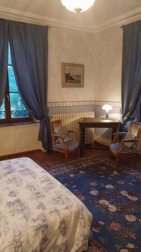 a bedroom with a bed and a table and chairs at La chambre bleue in Bussang