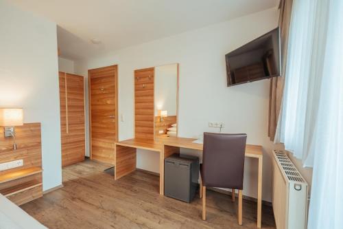 a room with a desk with a television and a chair at Hotel Gesser in Sillian