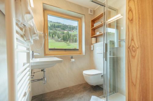 ein Bad mit einem WC, einem Waschbecken und einem Fenster in der Unterkunft Hotel Gesser in Sillian