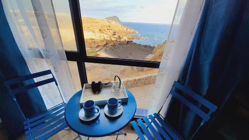 - une table bleue et des chaises dans une chambre avec vue sur l'océan dans l'établissement Los Abrigos Ocean relax, wifi, playas, à Los Abrigos