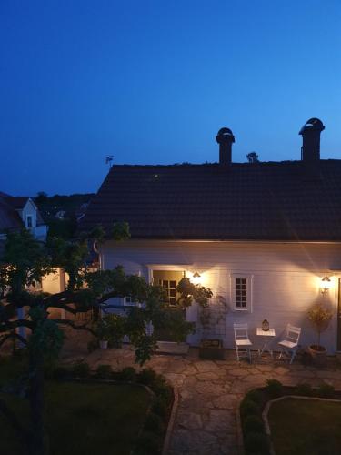 una casa blanca con 2 sillas y una mesa por la noche en Stenkullens gårdshus, en Borensberg