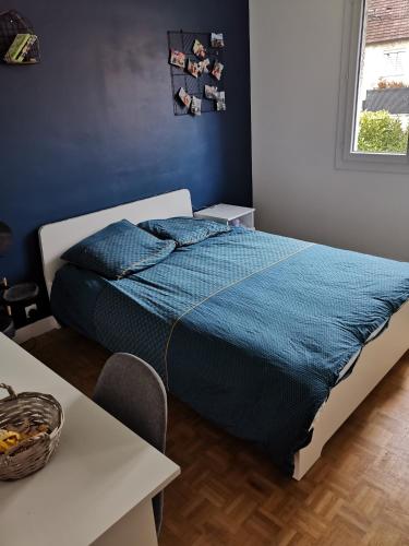 Schlafzimmer mit einem Bett mit blauer Bettwäsche und einem Tisch in der Unterkunft Le mans circuit 3 Chambres 1 à 6 personnes in Le Mans