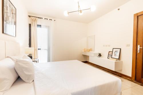 a white bedroom with a white bed and a window at LOFTS by Elegant Hospitality in Cairo