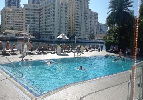 een zwembad waar mensen in zwemmen in een stad bij Amplio Studio en hotel Beachwalk Resort Miami in Hallandale Beach