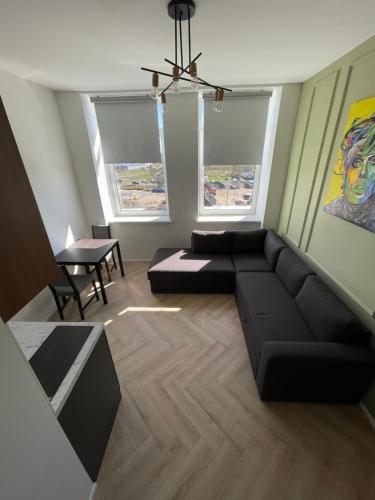 un soggiorno con divano nero e 2 finestre di Airport Apartment 14 Self Check-In Free parking a Vilnius