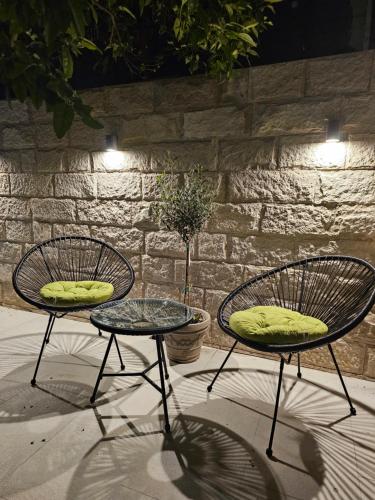 2 chaises et une table en face d'un mur de briques dans l'établissement Studio apartmani Vukasin, à Tivat