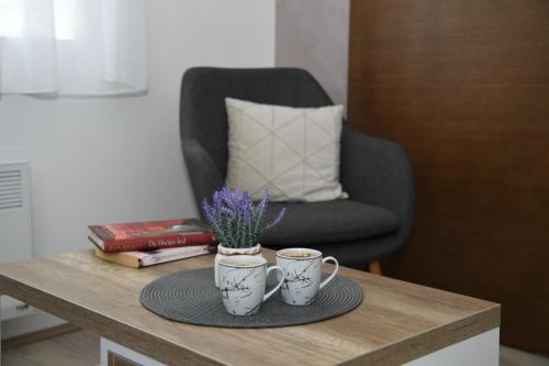 2 tazas de café en una mesa de madera con una silla en Apartman Zara en Jagodina