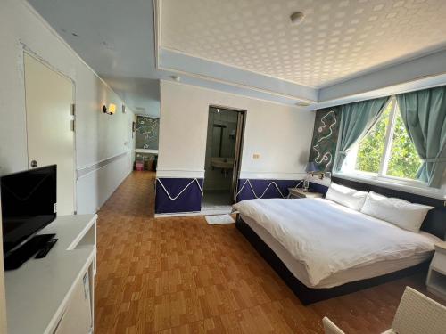 1 dormitorio con 1 cama y TV de pantalla plana en Dajenshan Hotel, en Kenting
