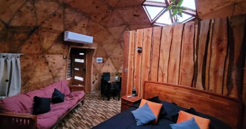 sala de estar con sofá púrpura y paredes de madera en Domos Mi Espacio Rustiko en San Carlos