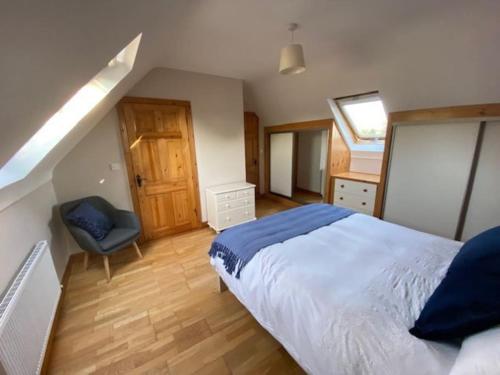 a bedroom with a large bed and a chair at Beechwood View in Kilrush