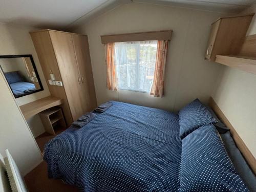 a bedroom with a blue bed and a window at Forget-me-not Holidays in Annalong