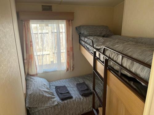a small room with two bunk beds and a window at Forget-me-not Holidays in Annalong