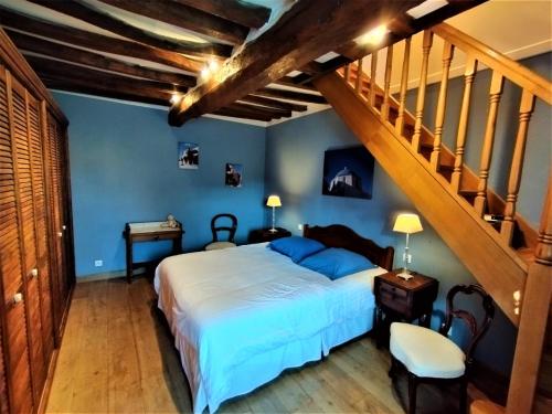 a bedroom with a bed with blue walls and a staircase at La Roselière in Sainte-Colombe